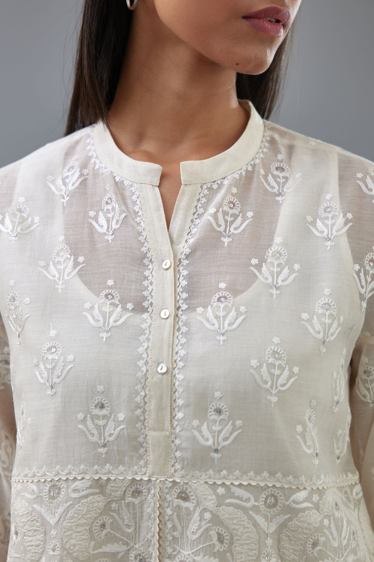 Off white cotton chanderi short top with heavy appliqué, highlighted with sequins, paired with off white cotton straight pants with appliqué and hand attached sequins detailing at bottom hem.
