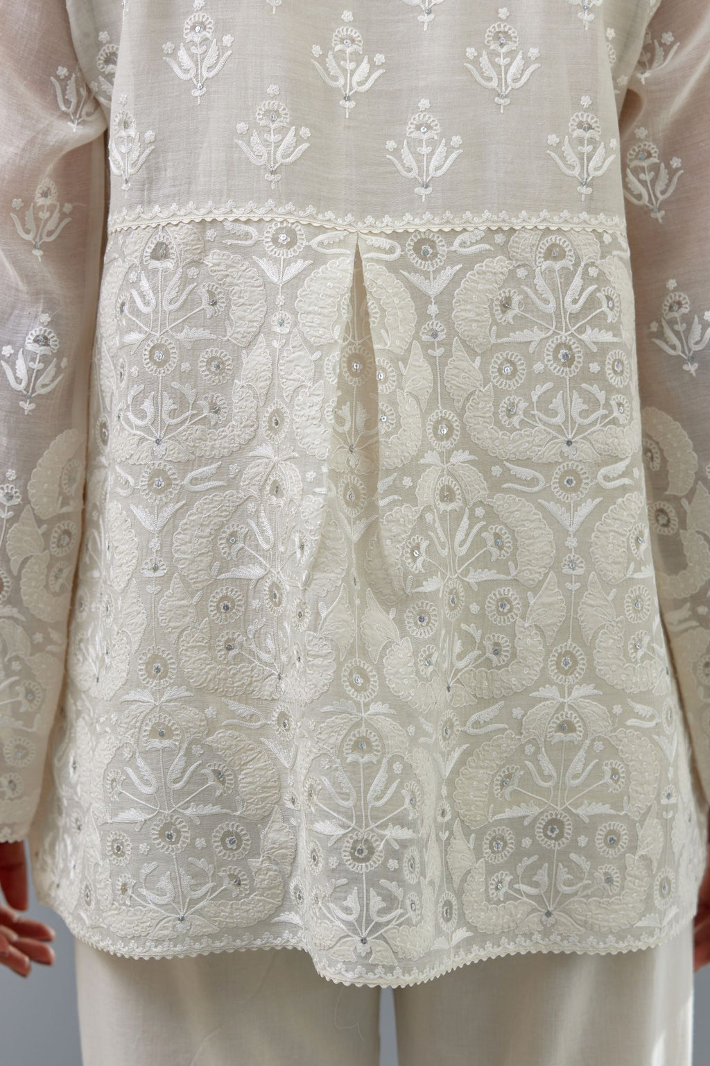 Off white cotton chanderi short top with heavy appliqué, highlighted with sequins, paired with off white cotton straight pants with appliqué and hand attached sequins detailing at bottom hem.
