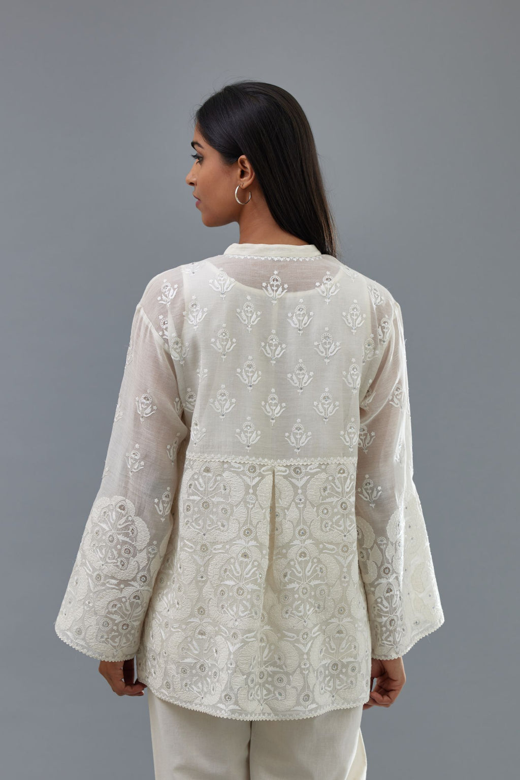 Off white cotton chanderi short top with heavy appliqué, highlighted with sequins, paired with off white cotton straight pants with appliqué and hand attached sequins detailing at bottom hem.