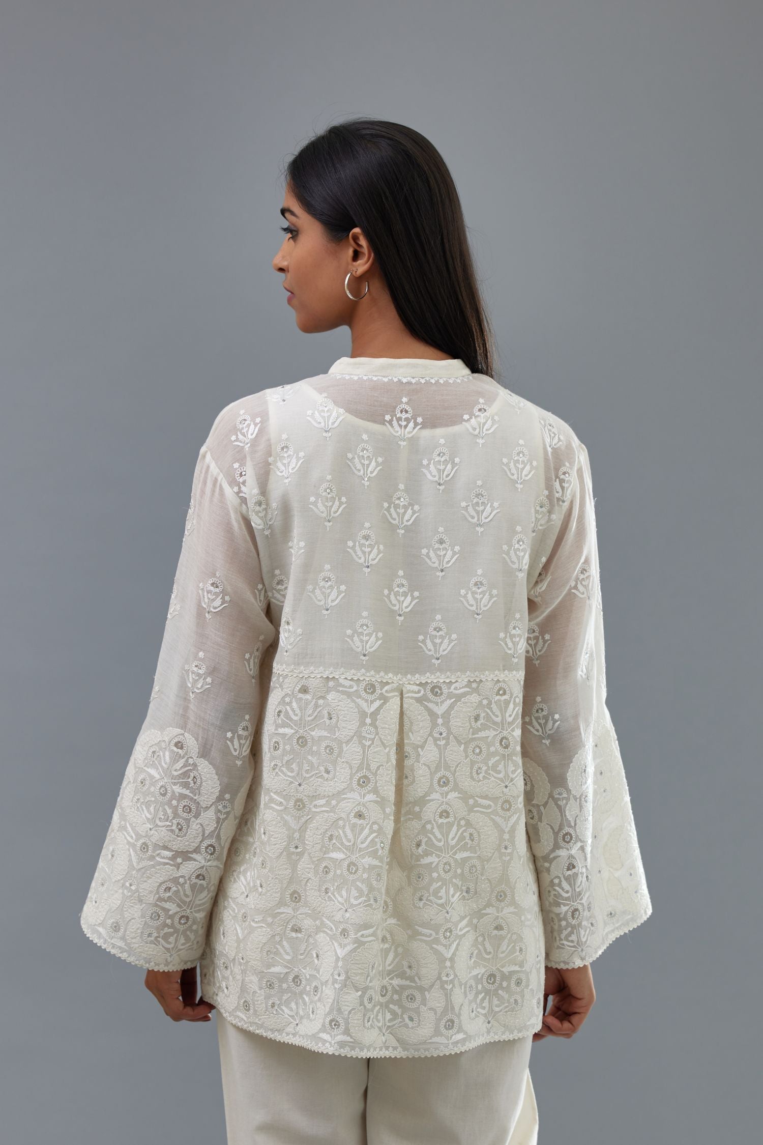 Off white cotton chanderi short top with heavy appliqué, highlighted with sequins, paired with off white cotton straight pants with appliqué and hand attached sequins detailing at bottom hem.