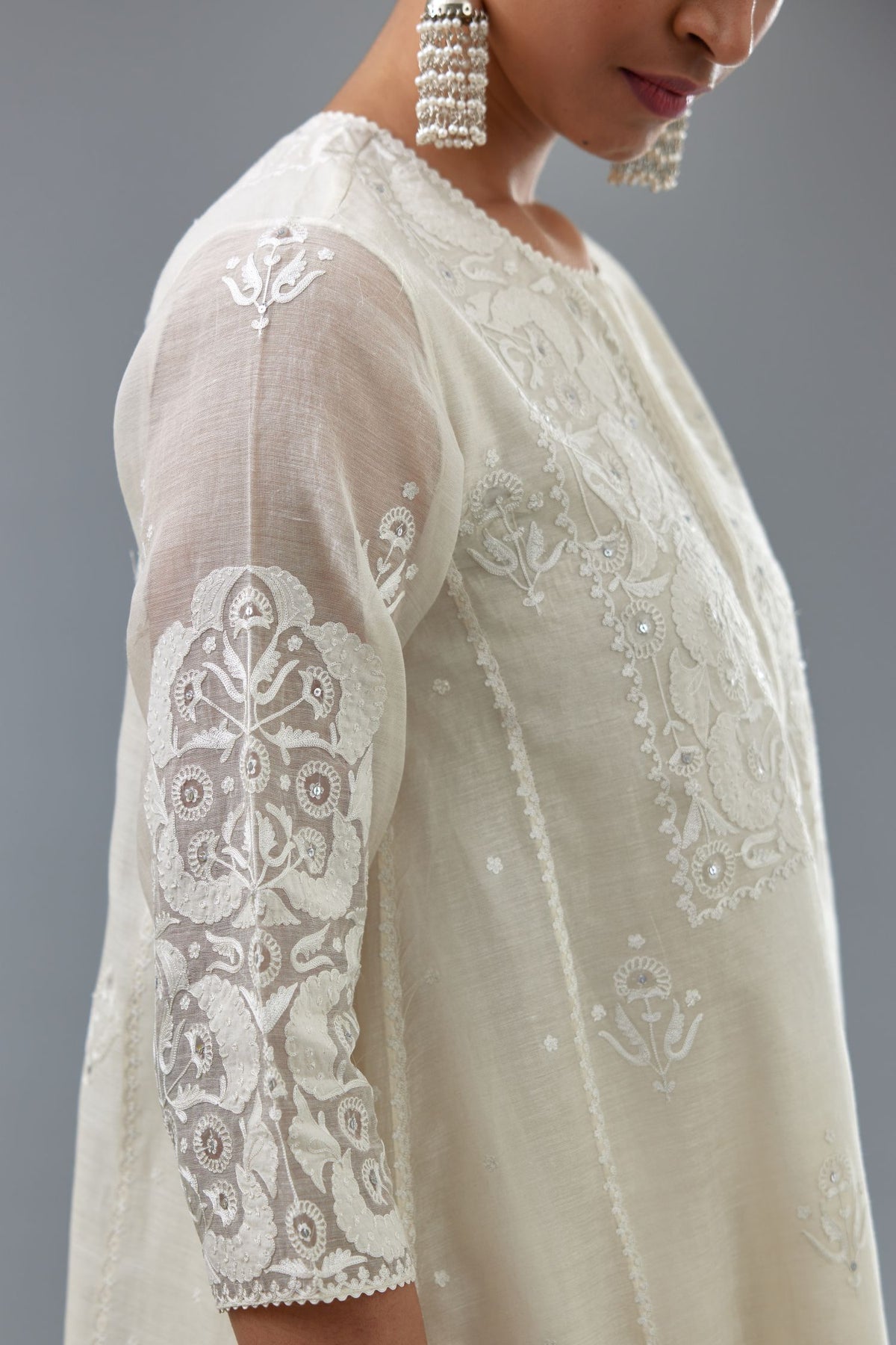 Off white A-line long kurta set with all-over tonal silk thread embroidery and cotton applique, highlighted with sequins work.