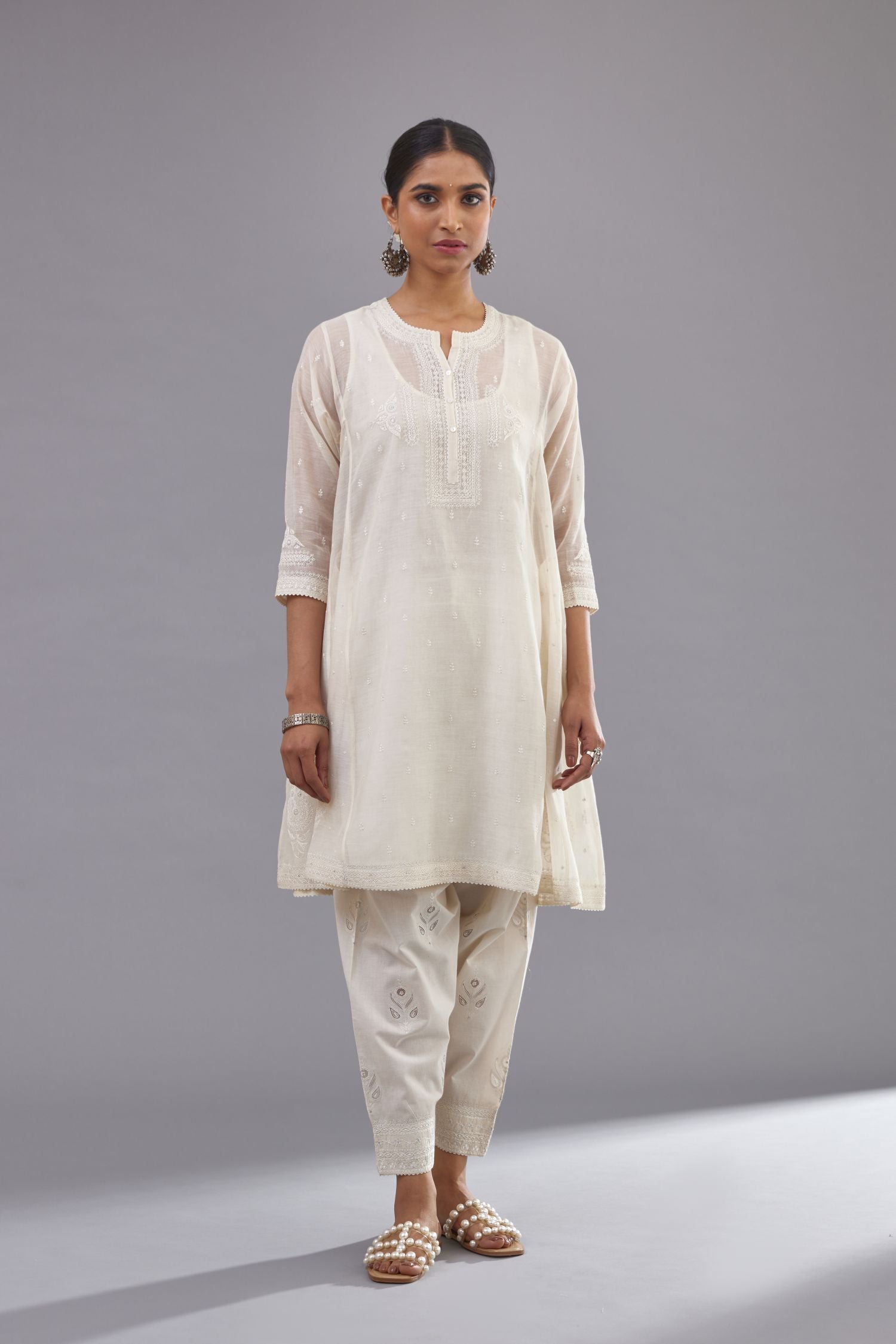 Off white cotton chanderi short kalidar phiran style kurta set with button placket neckline and dori and silk thraed embroidery all over.