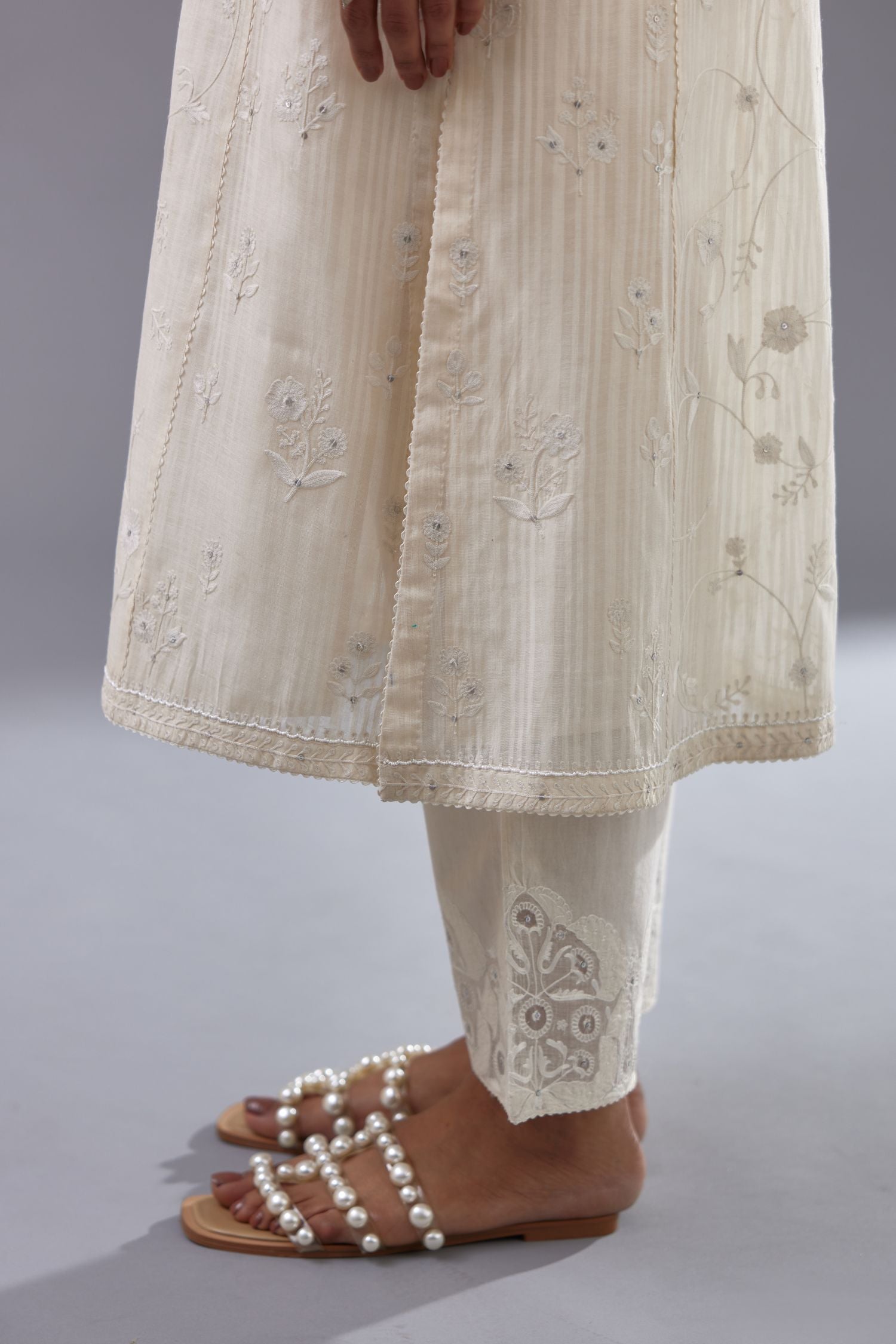 Off-white cotton chanderi kurta set with all-over jaal embroidery and small assorted flowers embroidery at side panells, highlighted with sequins handwork.