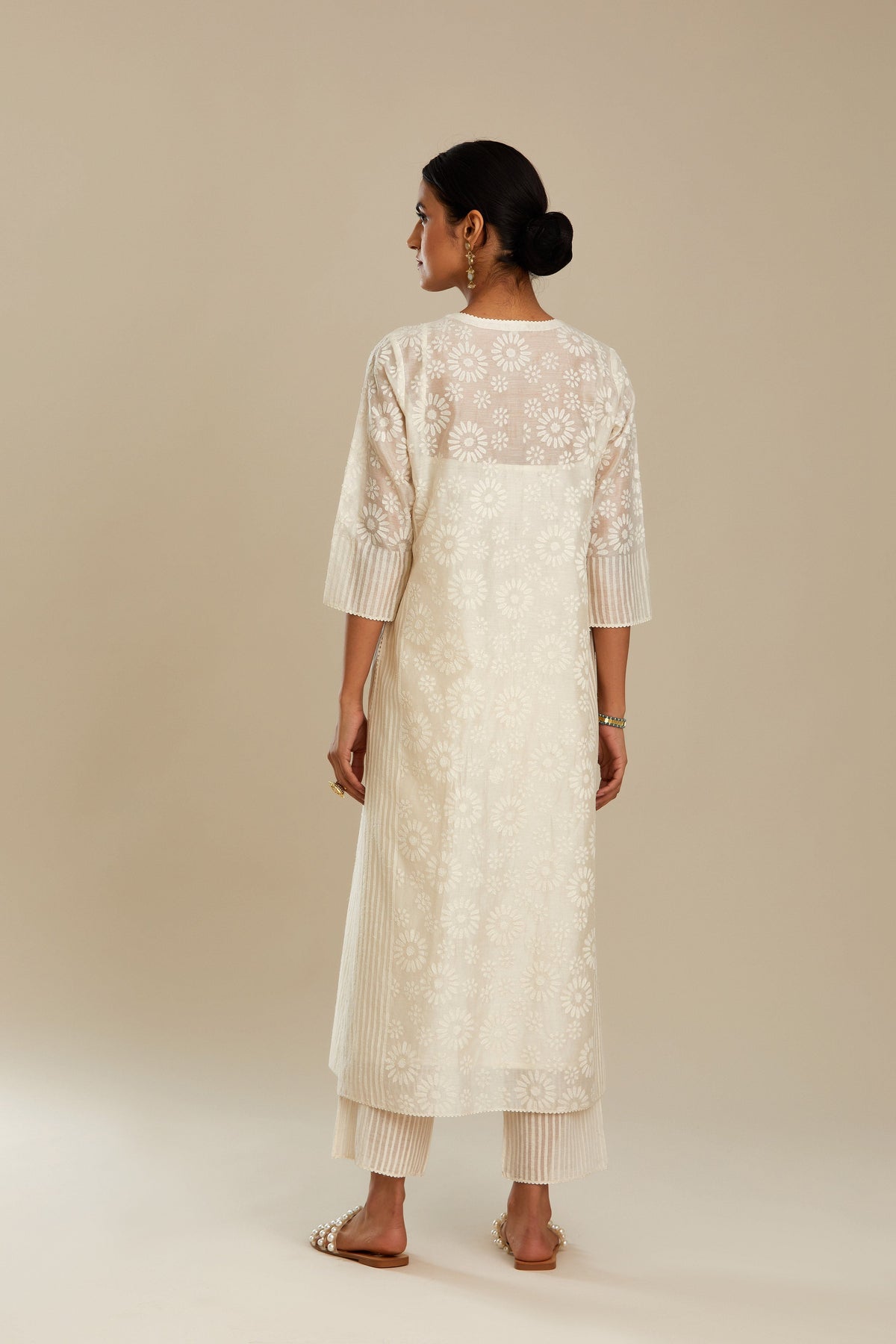 Off white silk chanderi straight kurta set with floral appliqué in center panel and striped cutwork at the sides.