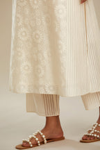 Off white silk chanderi straight kurta set with floral appliqué in center panel and striped cutwork at the sides.