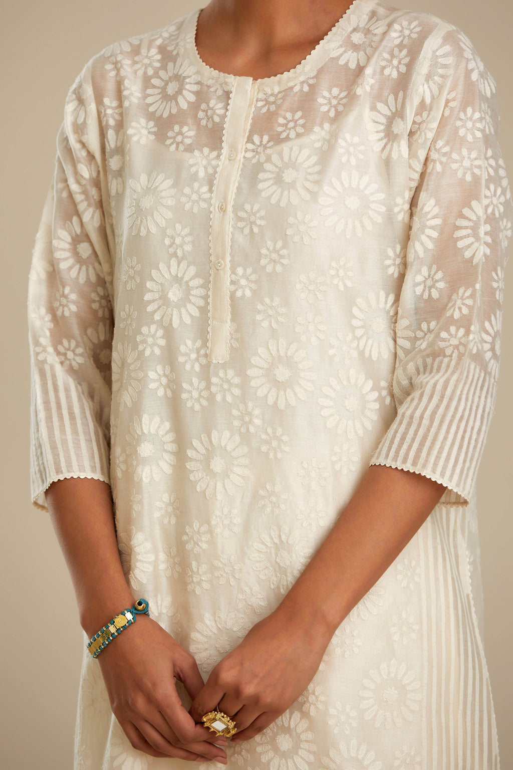 Off white silk chanderi straight kurta set with floral appliqué in center panel and striped cutwork at the sides.