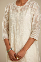 Off white silk chanderi straight kurta set with floral appliqué in center panel and striped cutwork at the sides.