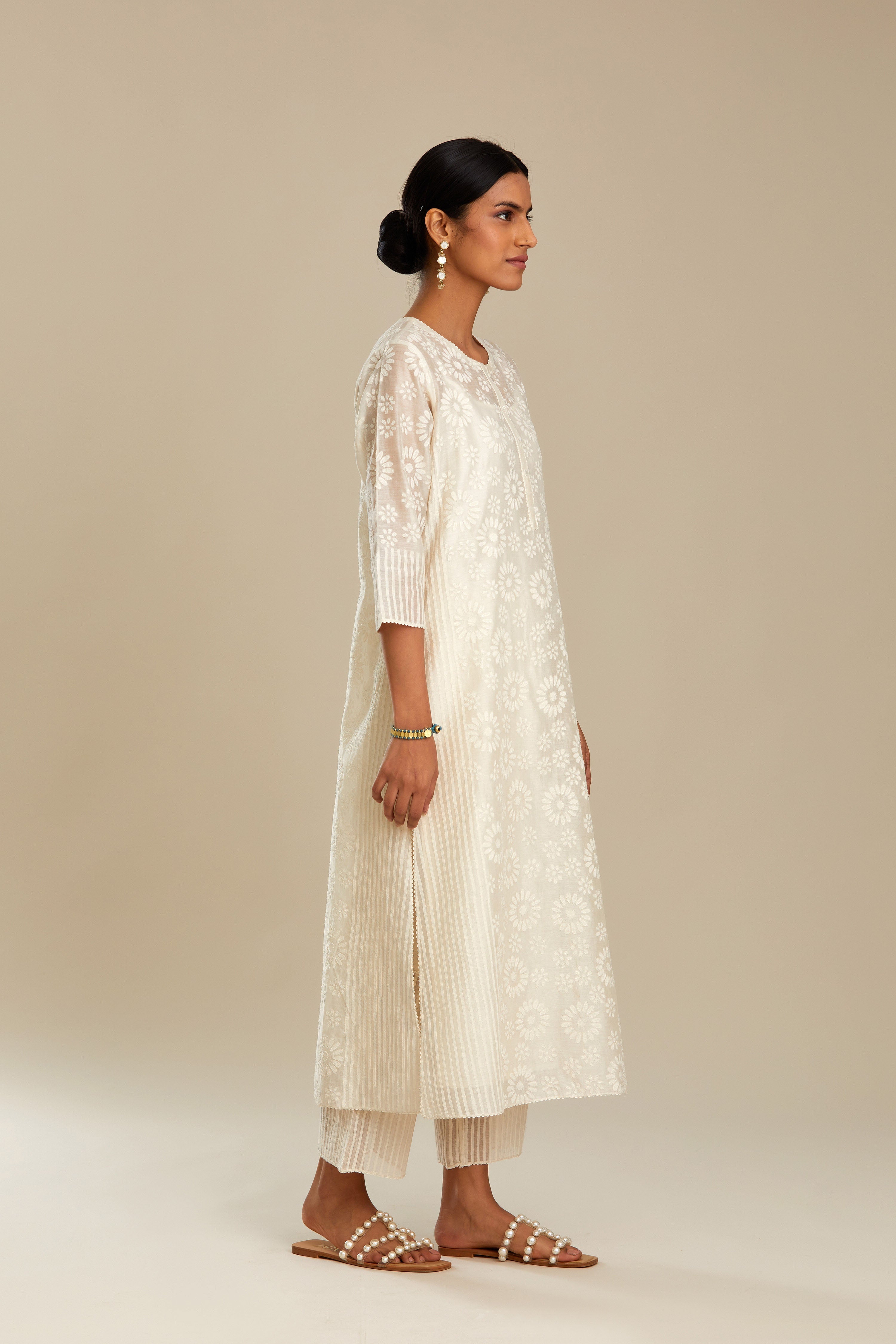 Off white silk chanderi straight kurta set with floral appliqué in center panel and striped cutwork at the sides.