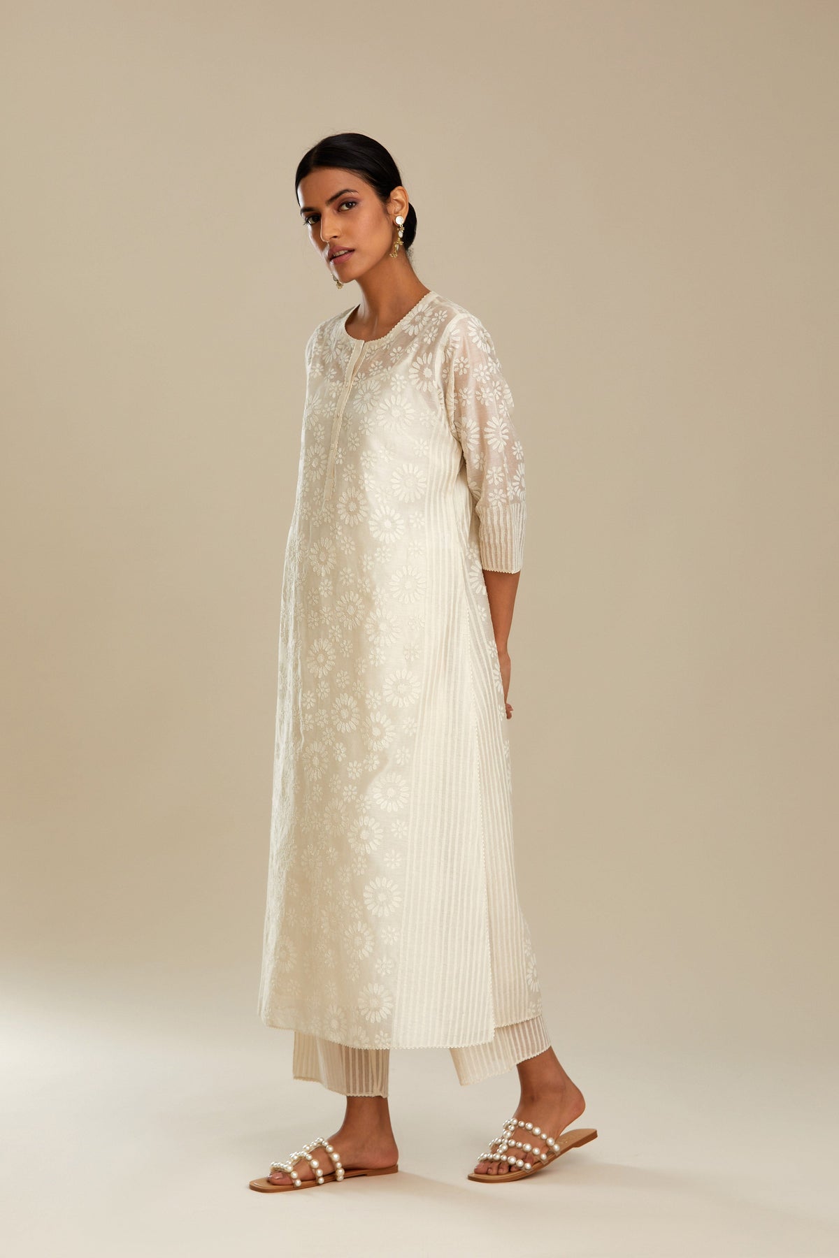 Off white silk chanderi straight kurta set with floral appliqué in center panel and striped cutwork at the sides.
