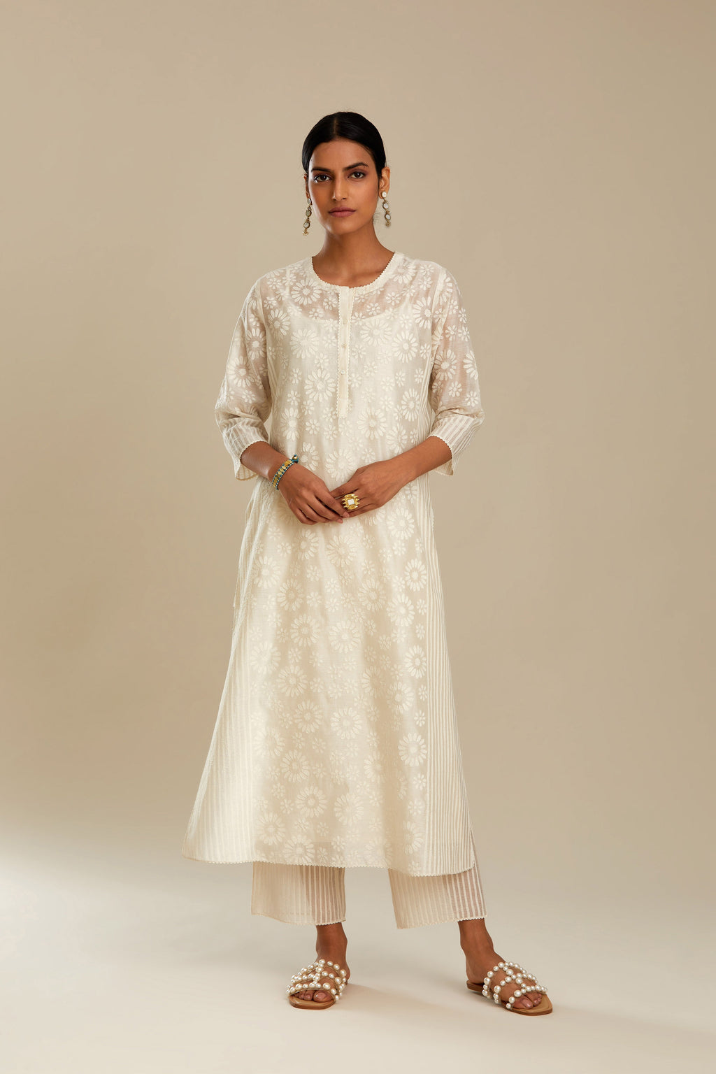 Off white silk chanderi straight kurta set with floral appliqué in center panel and striped cutwork at the sides.