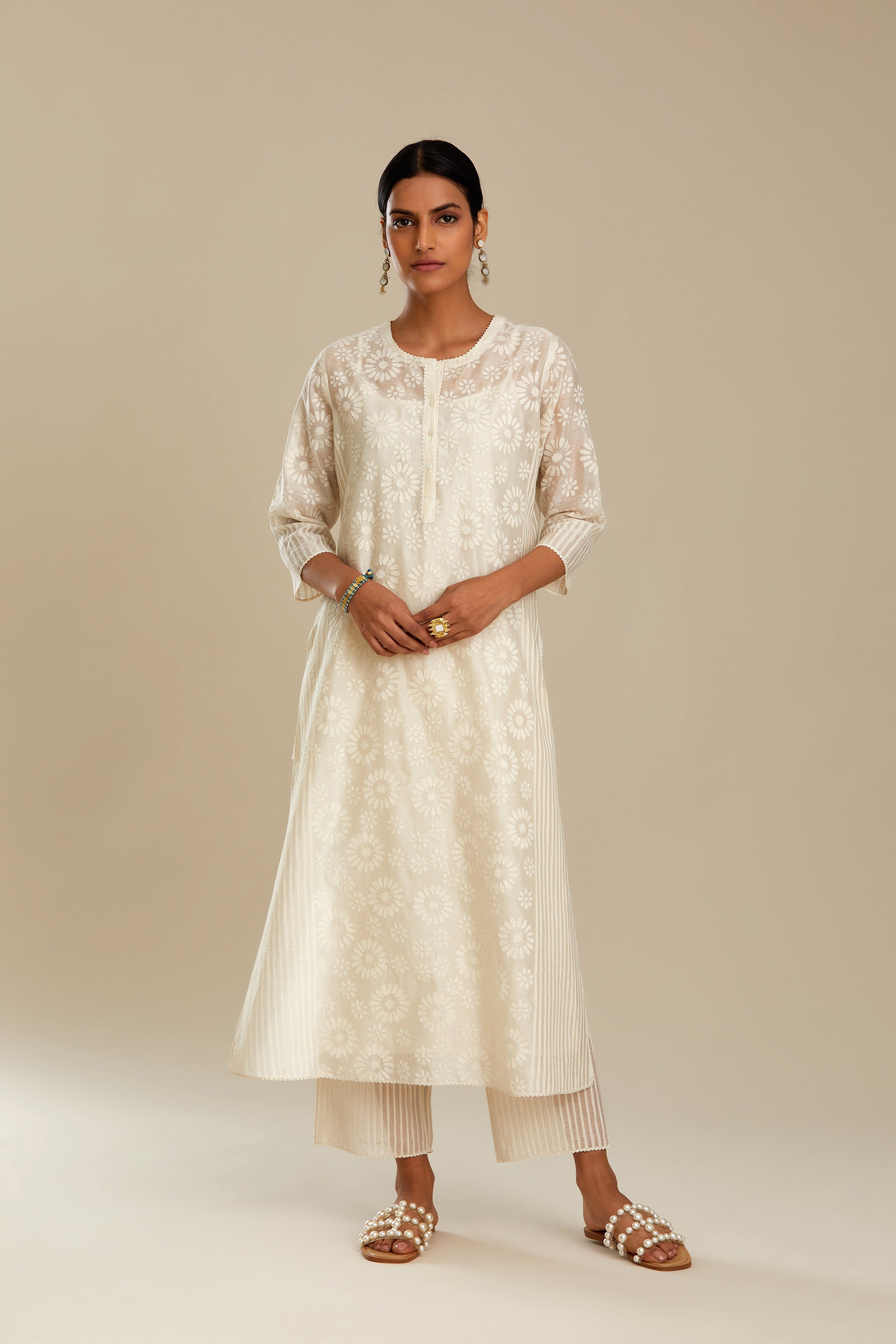 Off white silk chanderi straight kurta set with floral appliqué in center panel and striped cutwork at the sides.