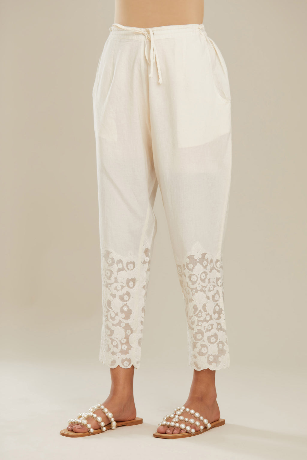 Off white cotton narrow pants with appliqué and hand attached sequins detailing. (Pants)