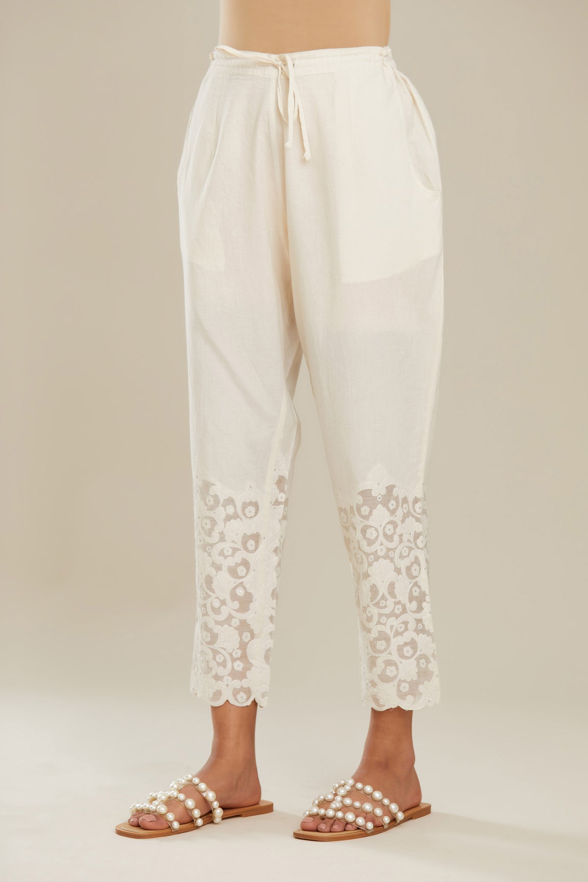 Off white cotton narrow pants with appliqué and hand attached sequins detailing. (Pants)