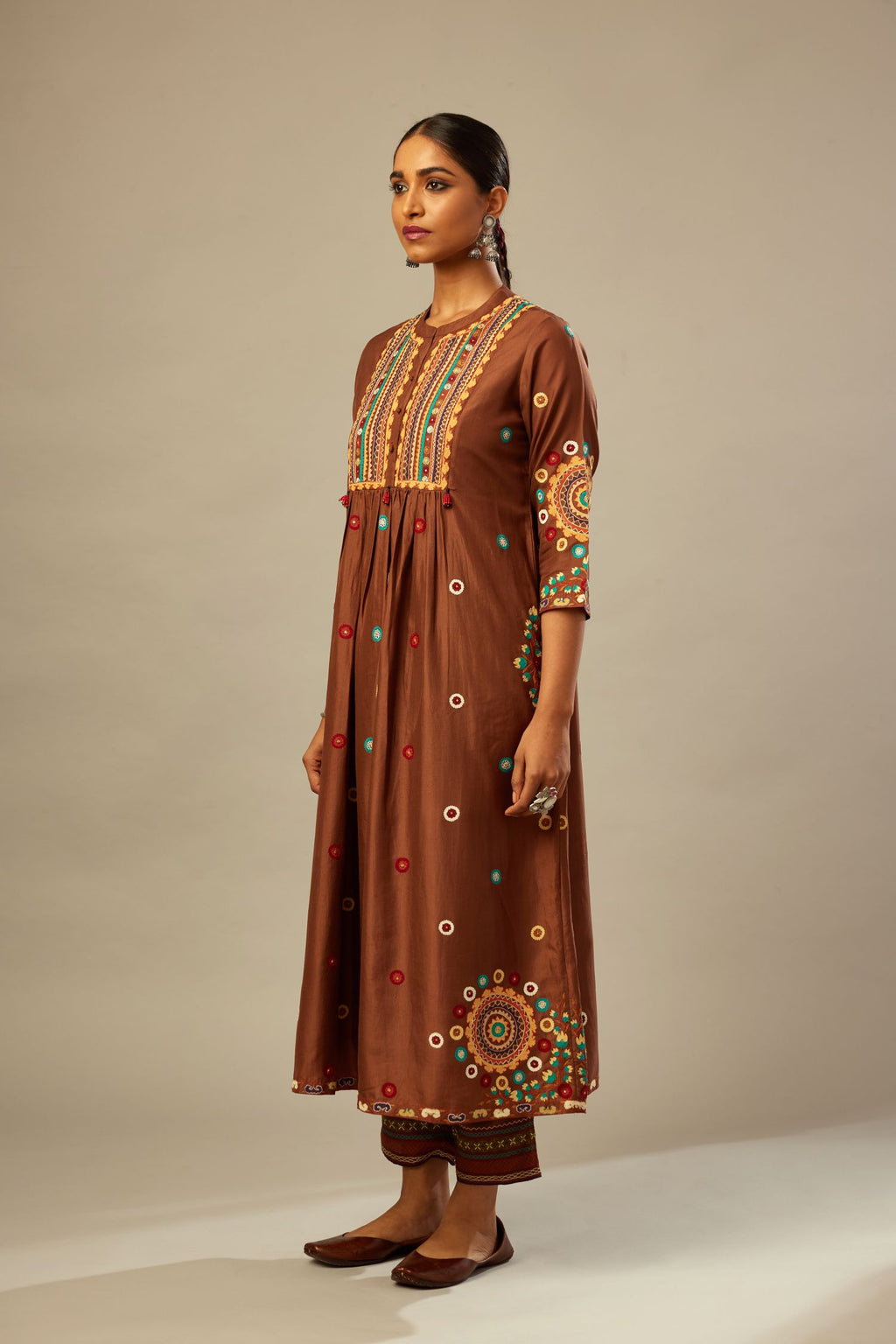Brown silk gathered kurta-dress set with appliqué stripes along with aari threadwork flowers and floral trellises along with a circular appliqued motif.
