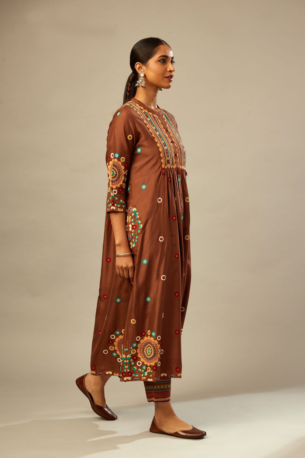 Brown silk gathered kurta-dress set with appliqué stripes along with aari threadwork flowers and floral trellises along with a circular appliqued motif.