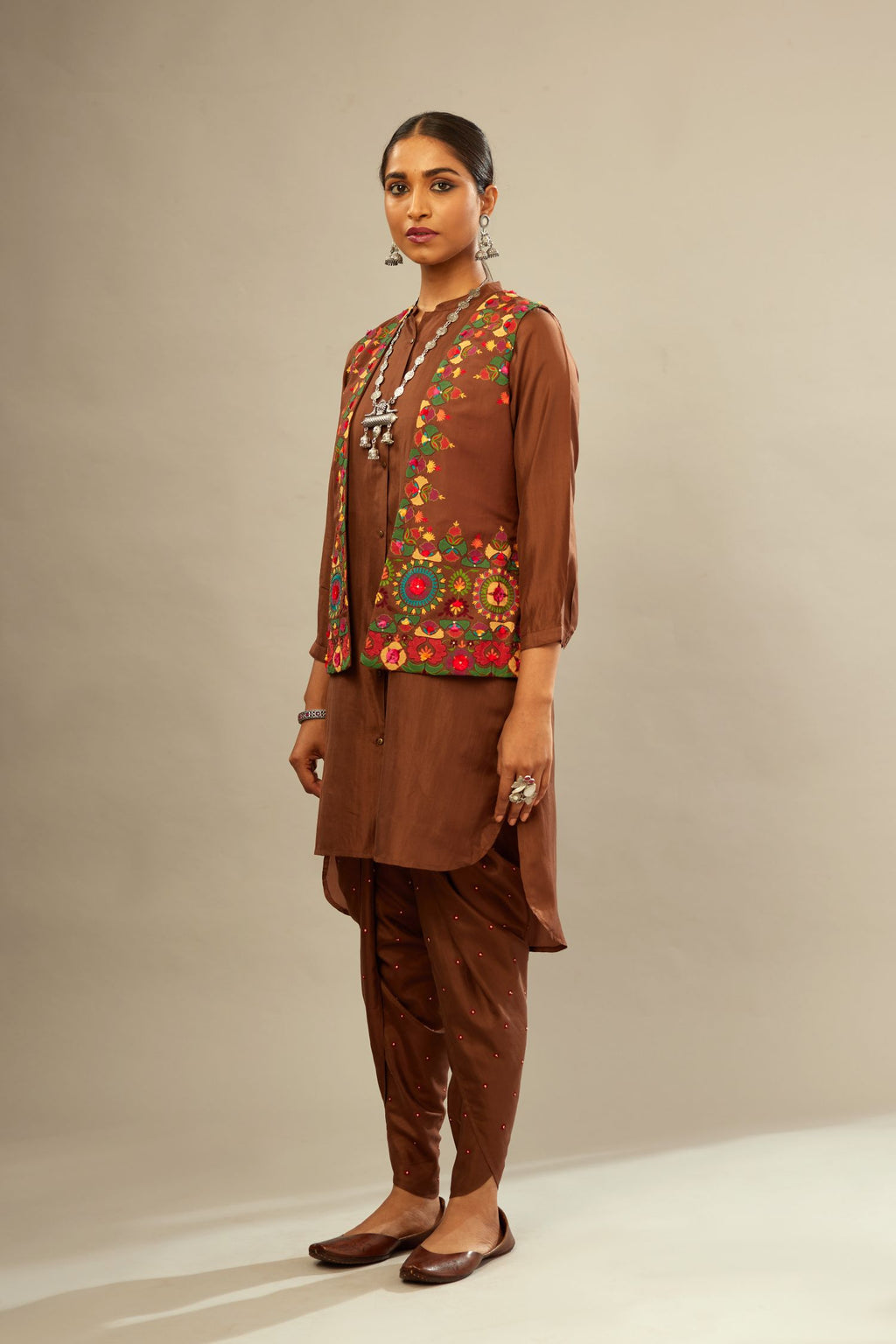 A four piece set in Brown silk comprising of a short kurta with front button placket, worn with a short waistcoat jacket.