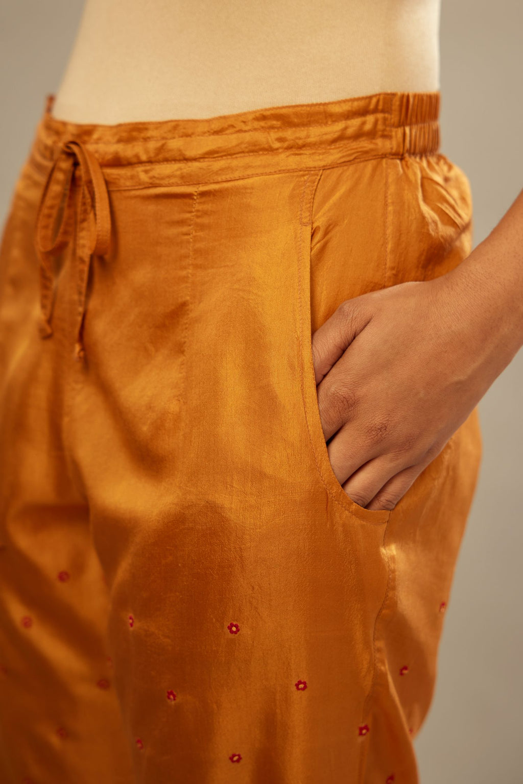Mustard silk straight pants detailed with small flower embroidery at bottom.