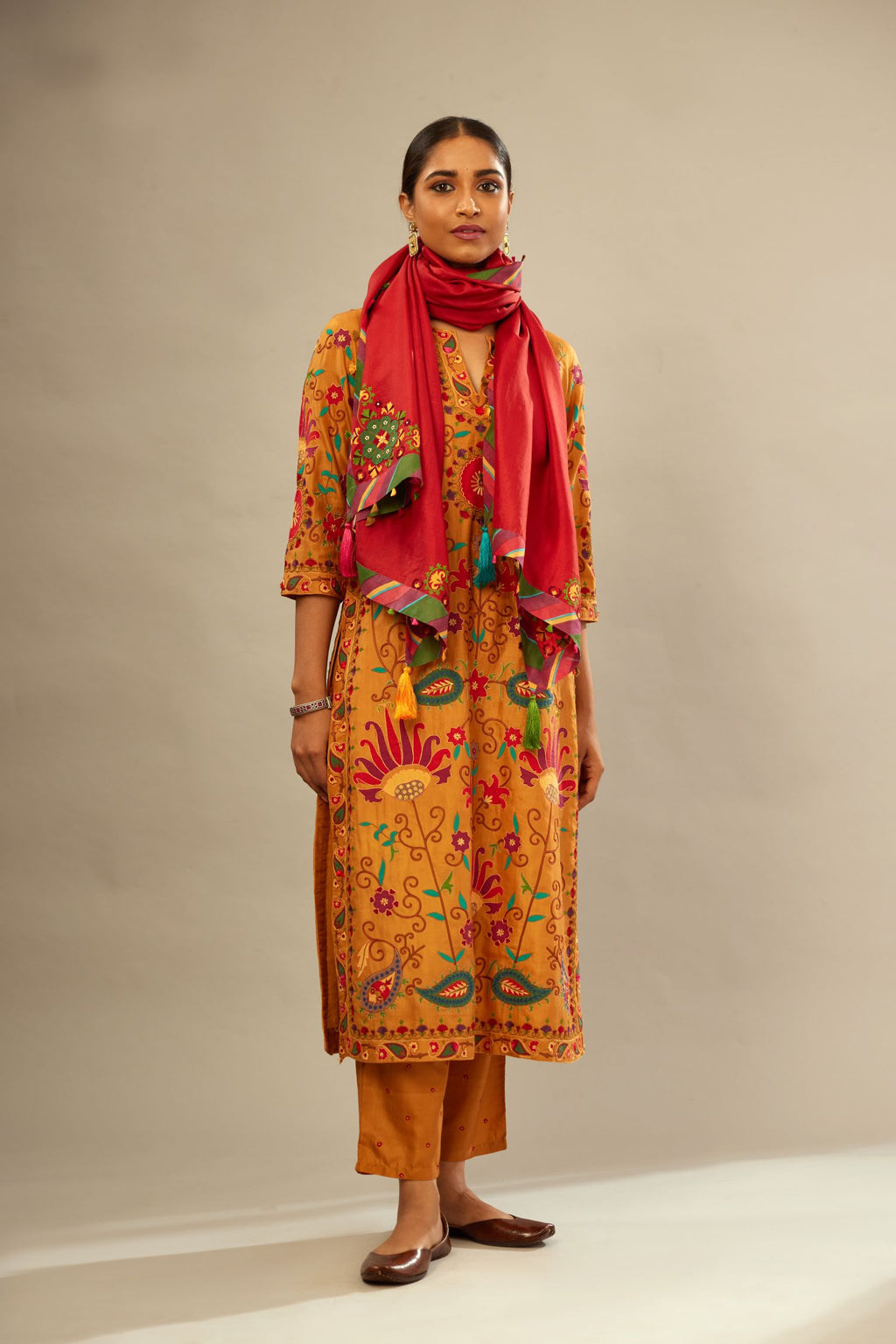Mustard straight kurta set, fully embroidered with bold appliqué flowers, multi-colored aari threadwork and silk tassels.