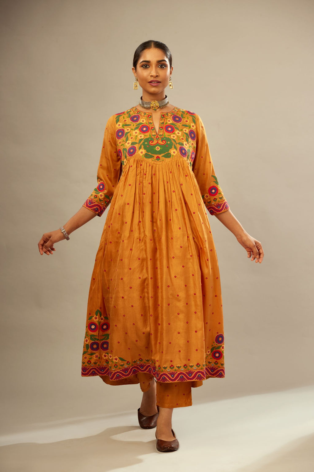 Mustard silk kurta-dress set with a wavy high-waist and fine gathers. The yoke is fully embroidered with colorful circular appliqué and aari thread work.