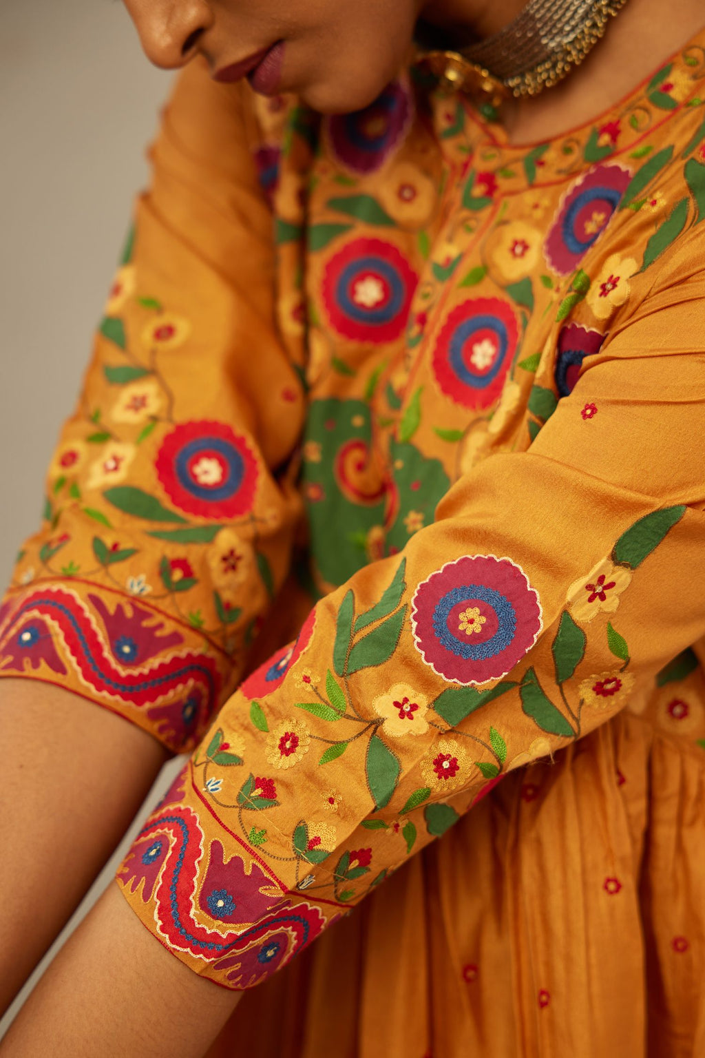 Mustard silk kurta-dress set with a wavy high-waist and fine gathers. The yoke is fully embroidered with colorful circular appliqué and aari thread work.