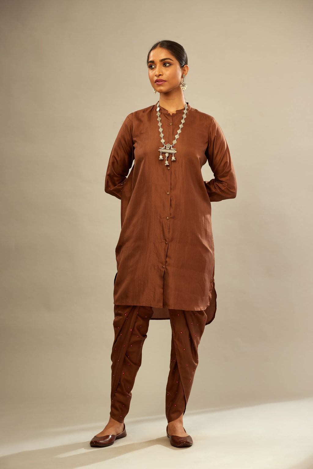 A four piece set in Brown silk comprising of a short kurta with front button placket, worn with a short waistcoat jacket.