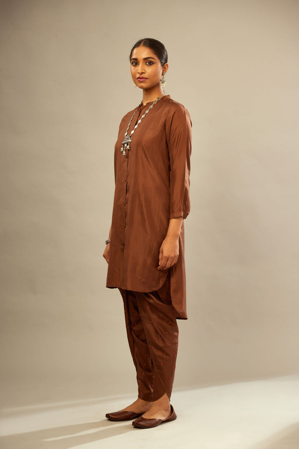 A four piece set in Brown silk comprising of a short kurta with front –  Kora India