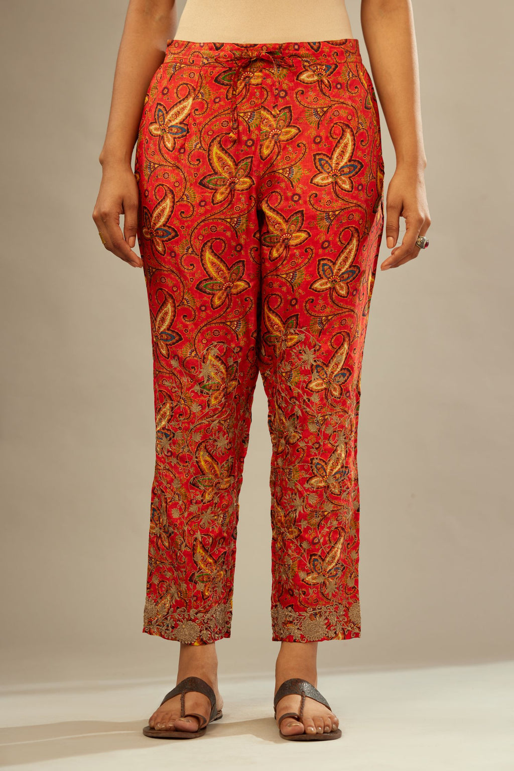 Burnt orange digital printed fine silk straight pants with heavy golden zari and dori embroidery at bottom.