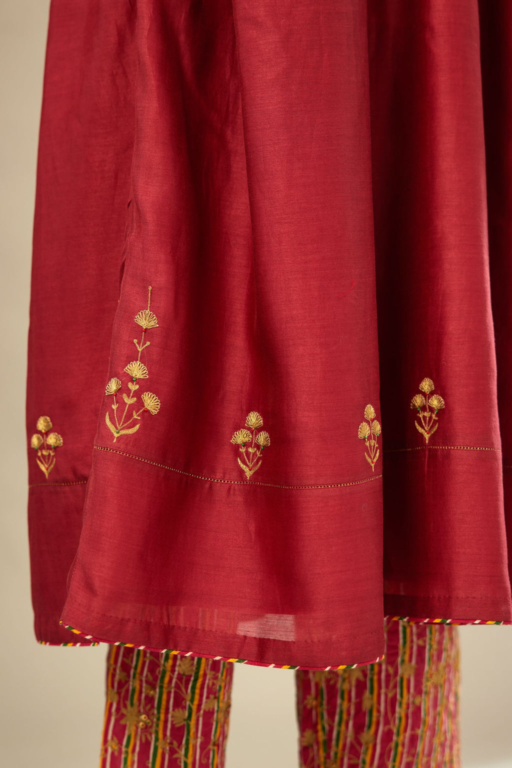 Deep wine long kurta set with wavy waistline detailed with golden zari embroidery