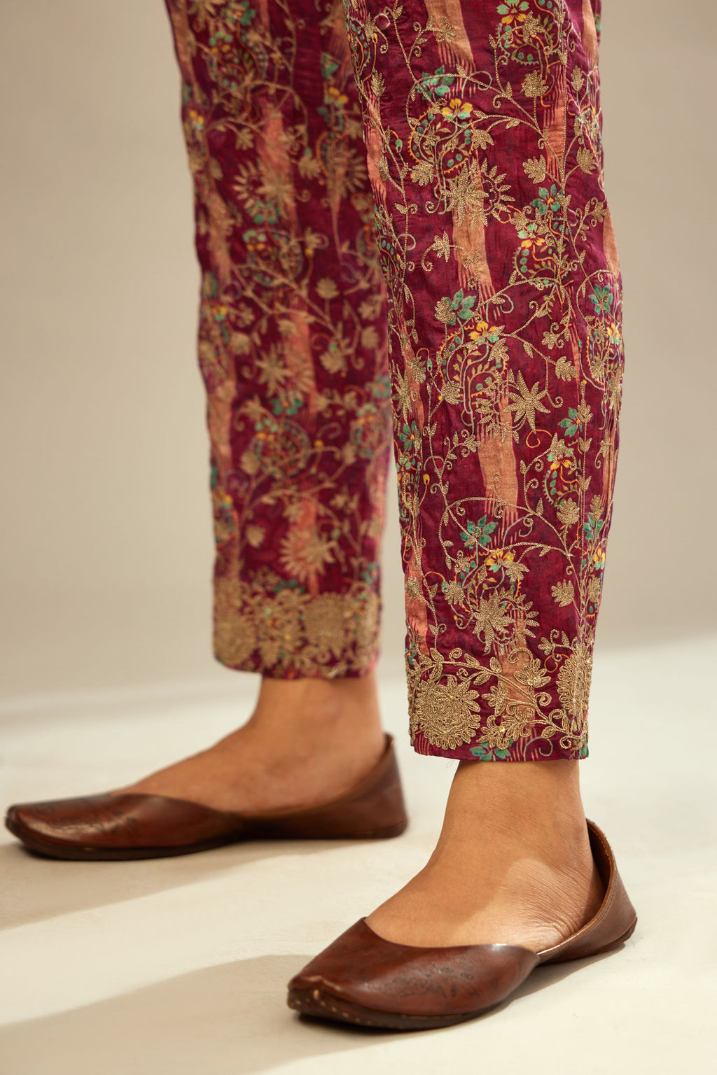 Deep wine digital printed fine silk straight pants with heavy golden zari and dori embroidery at bottom.