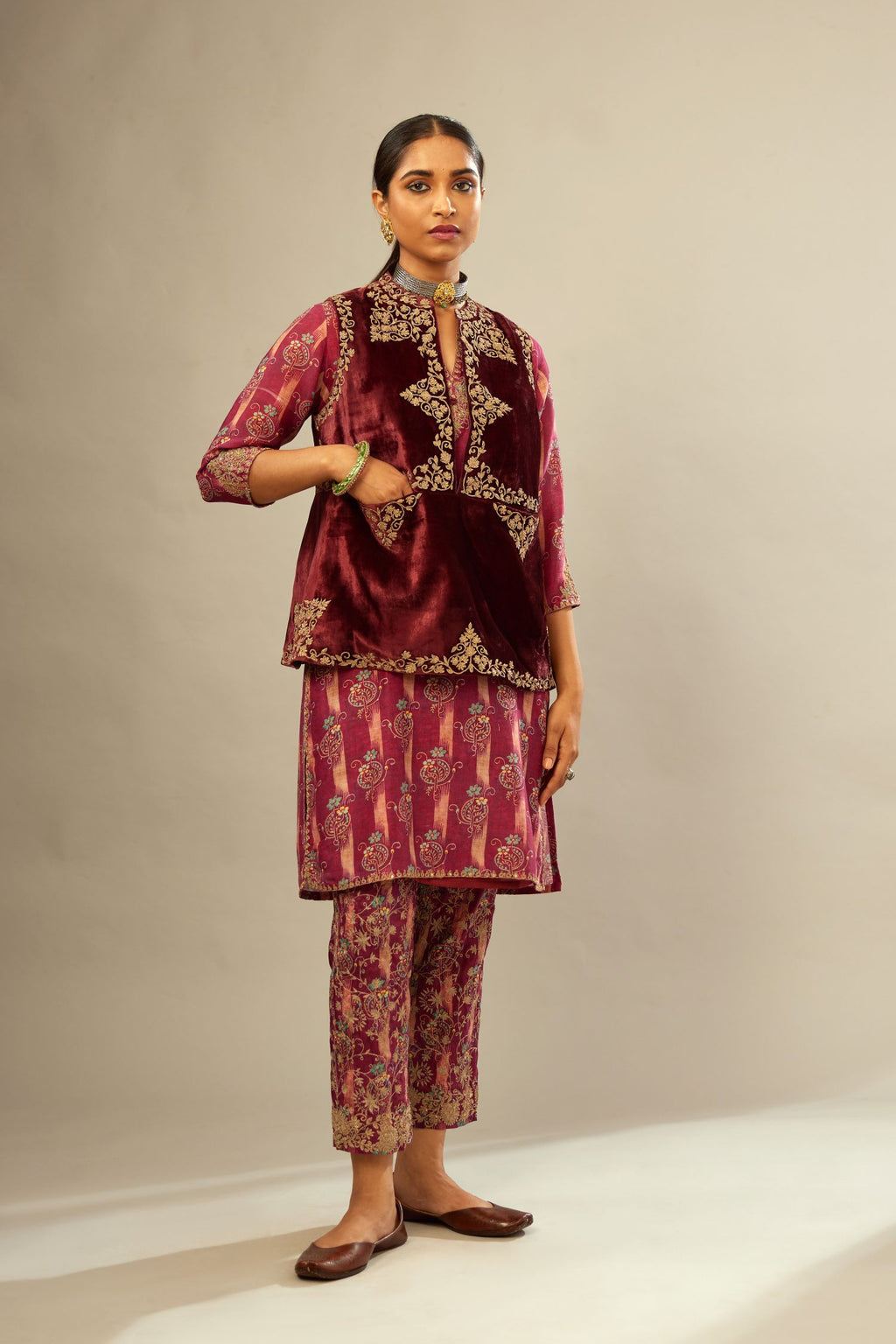 Maroon easy fit, short, sleeveless, silk-velvet jacket, embellished with antique gold embroidery. .