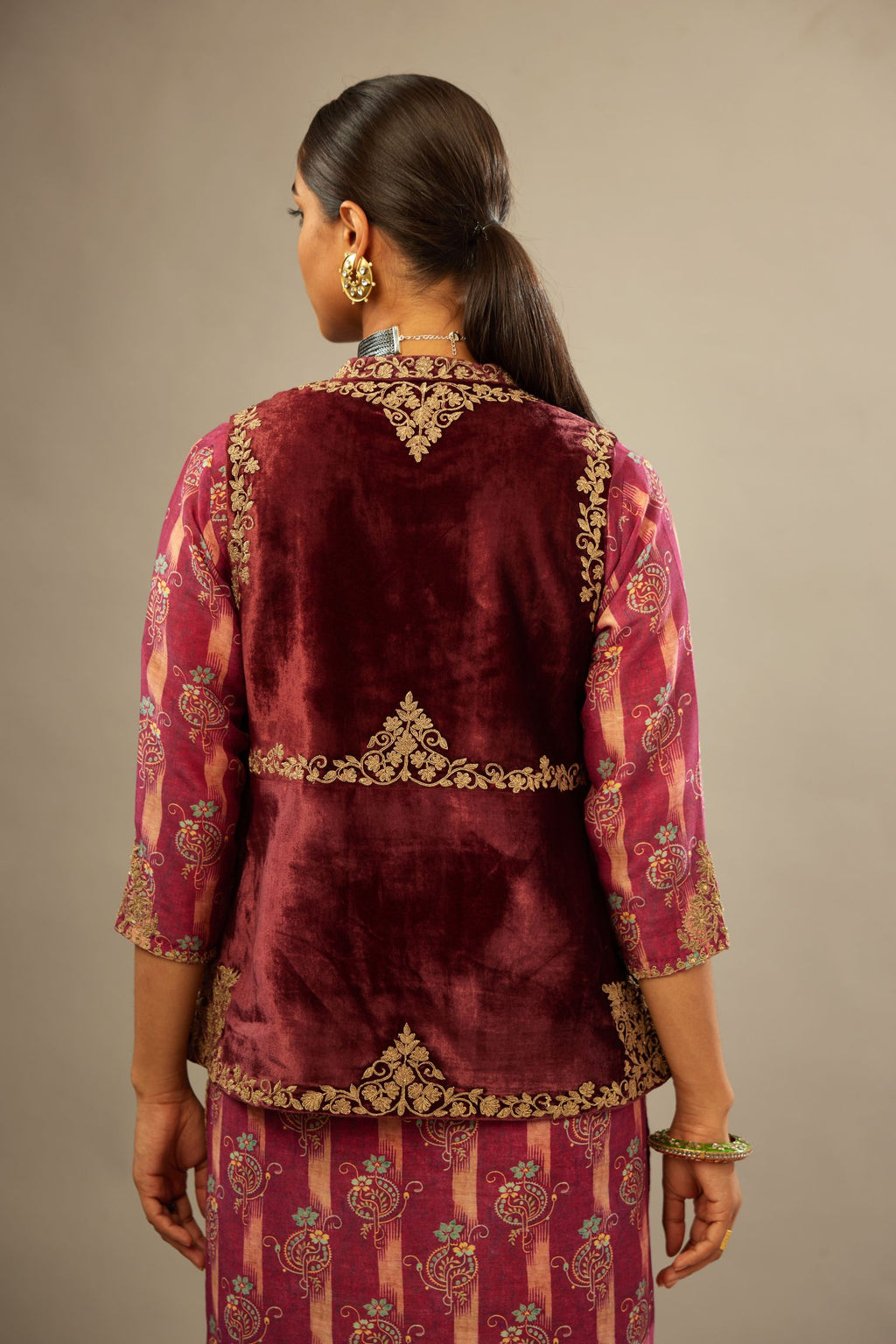 Maroon easy fit, short, sleeveless, silk-velvet jacket, embellished with antique gold embroidery. .