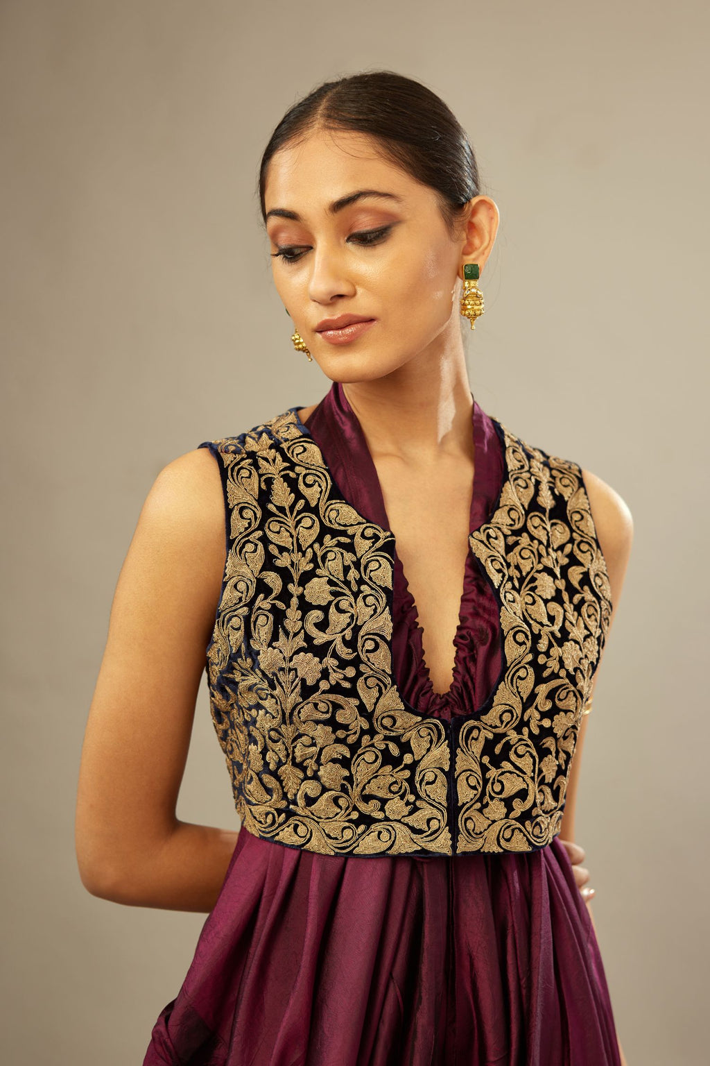 Wine silk long free size dress with asymmetric hem and side pockets, paired with navy blue silk velvet short jacket with light gold dori embroidery all-over the jacket.