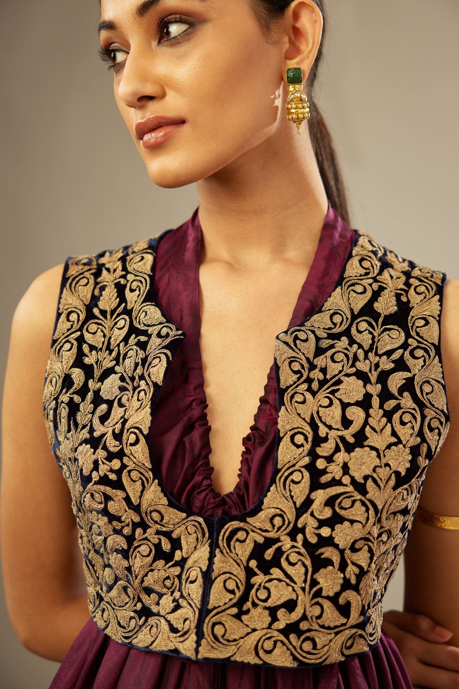 Wine silk long free size dress with asymmetric hem and side pockets, paired with navy blue silk velvet short jacket with light gold dori embroidery all-over the jacket.