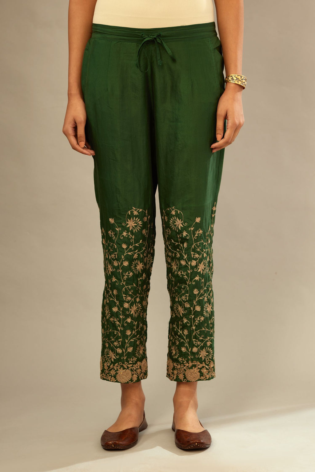 Green fine silk straight pants with heavy golden zari and dori embroidery at bottom.