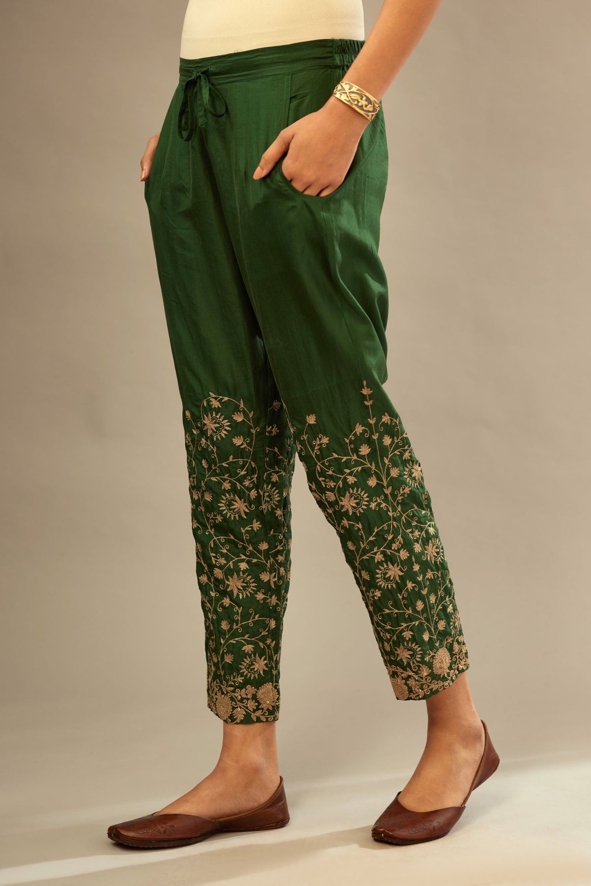 Green fine silk straight pants with heavy golden zari and dori embroidery at bottom.