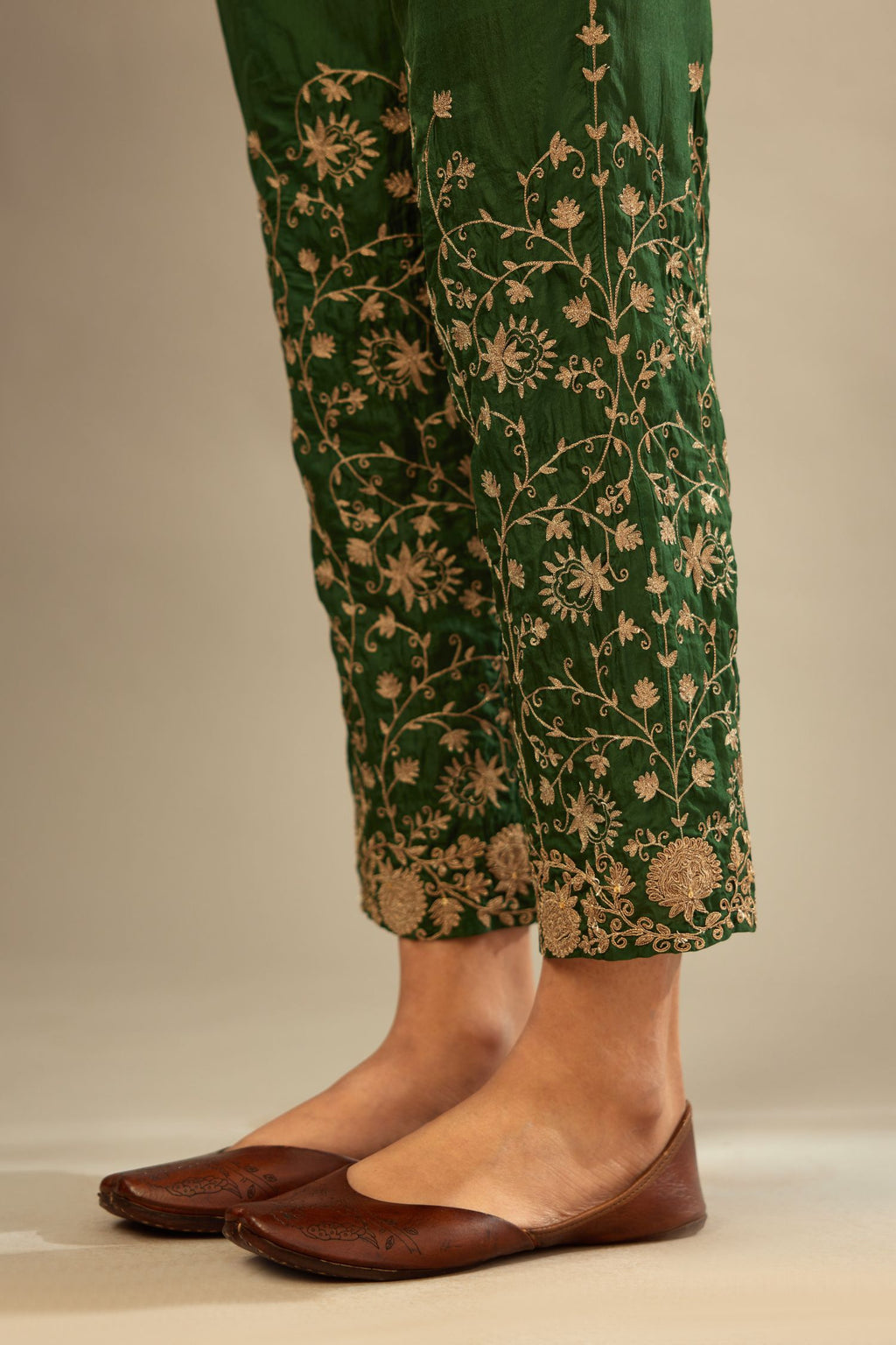 Green fine silk straight pants with heavy golden zari and dori embroidery at bottom.