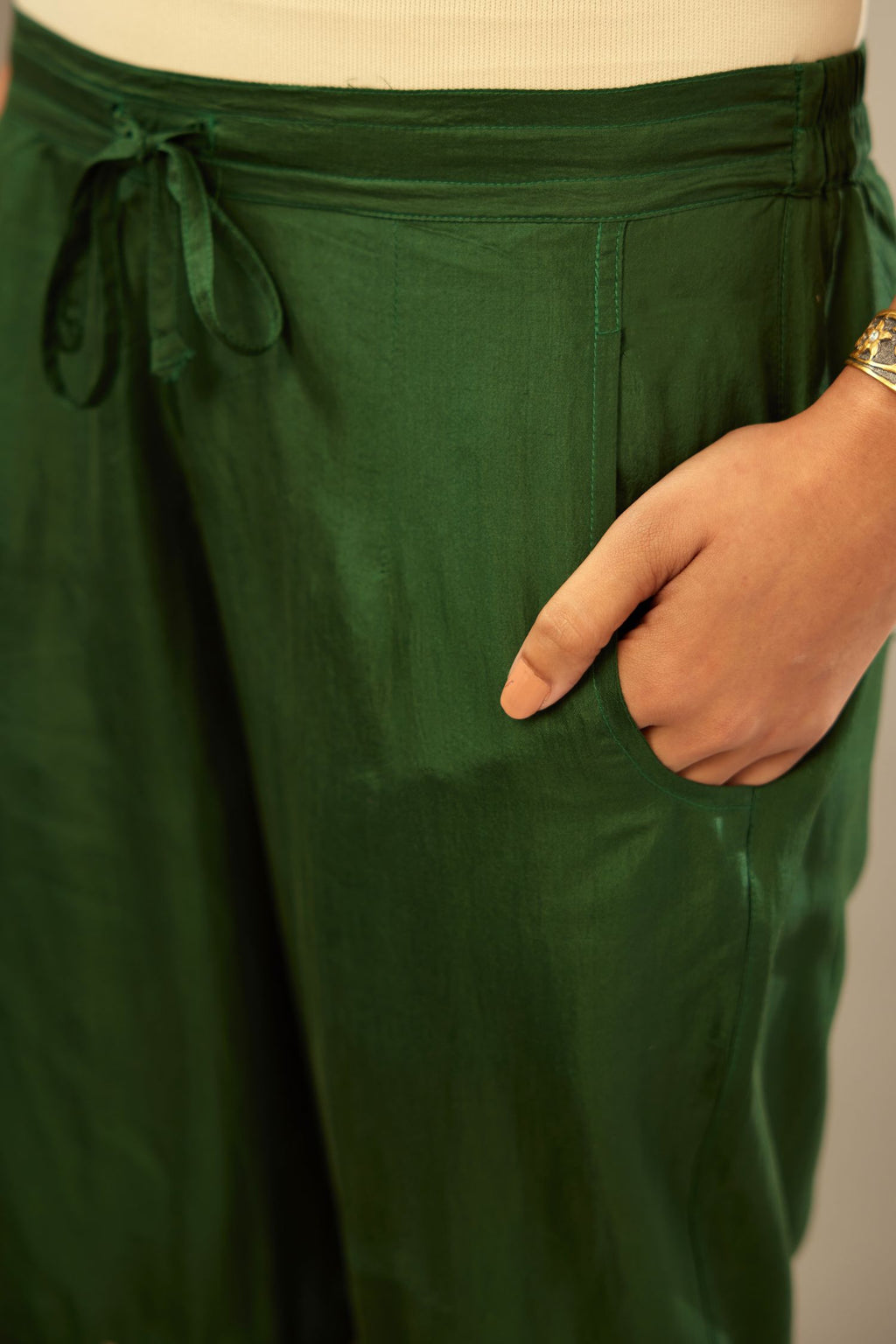Green fine silk straight pants with heavy golden zari and dori embroidery at bottom.