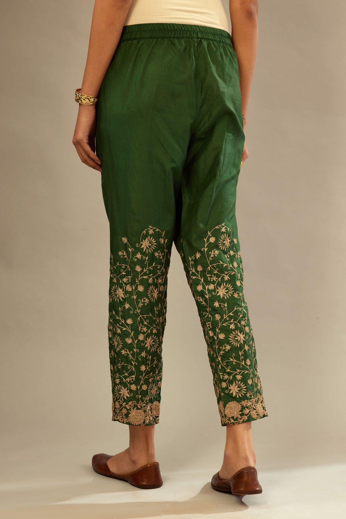 Green fine silk straight pants with heavy golden zari and dori embroidery at bottom.