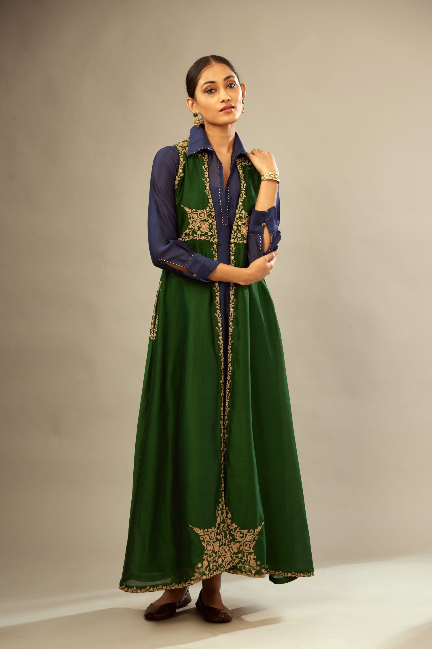Green long silk chanderi front open sleeveless jacket set with gold dori embroidery detailing, highlighted with gold sequin work.