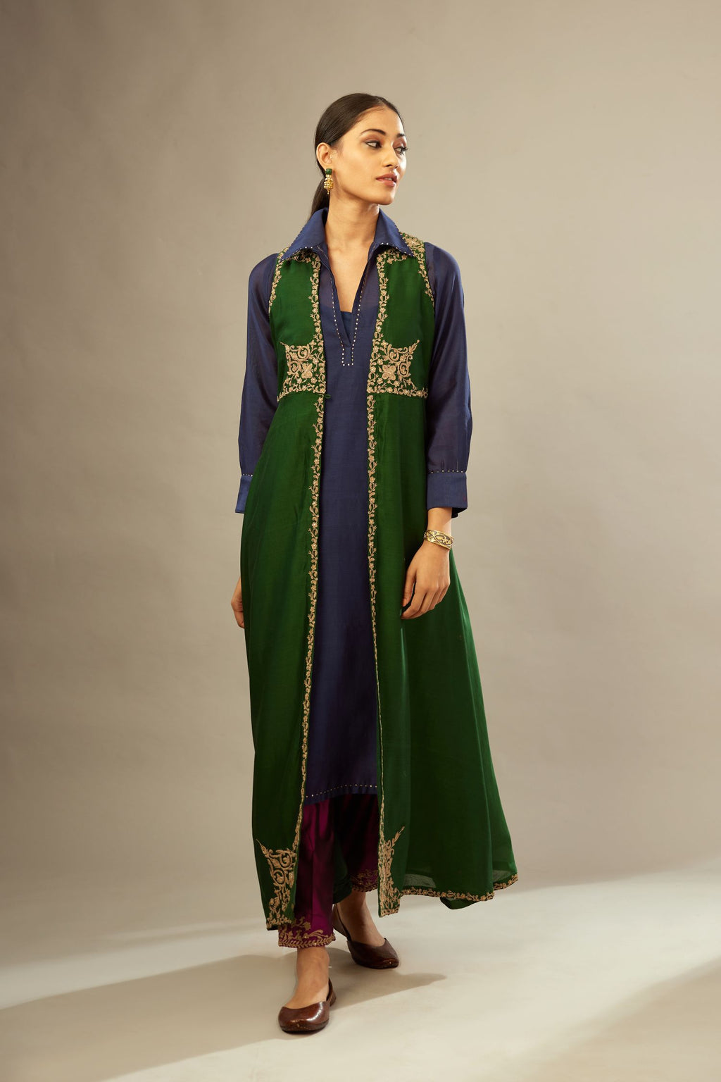 Green long silk chanderi front open sleeveless jacket set with gold dori embroidery detailing, highlighted with gold sequin work.