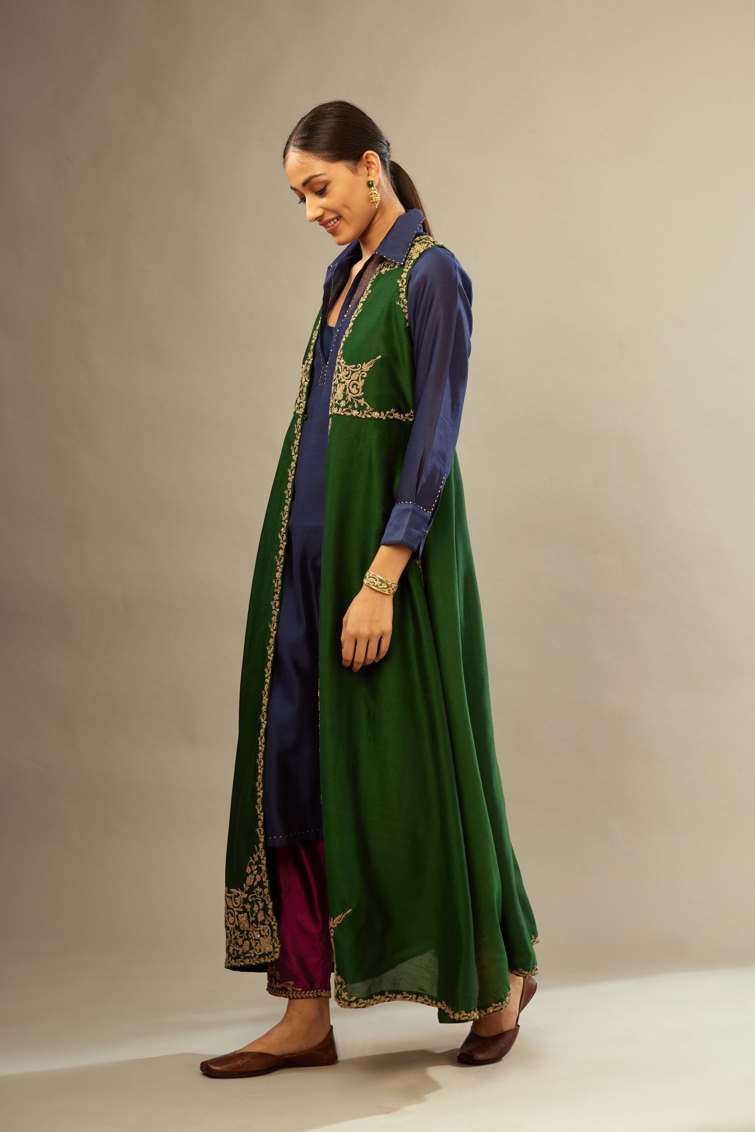 Green long silk chanderi front open sleeveless jacket set with gold dori embroidery detailing, highlighted with gold sequin work.