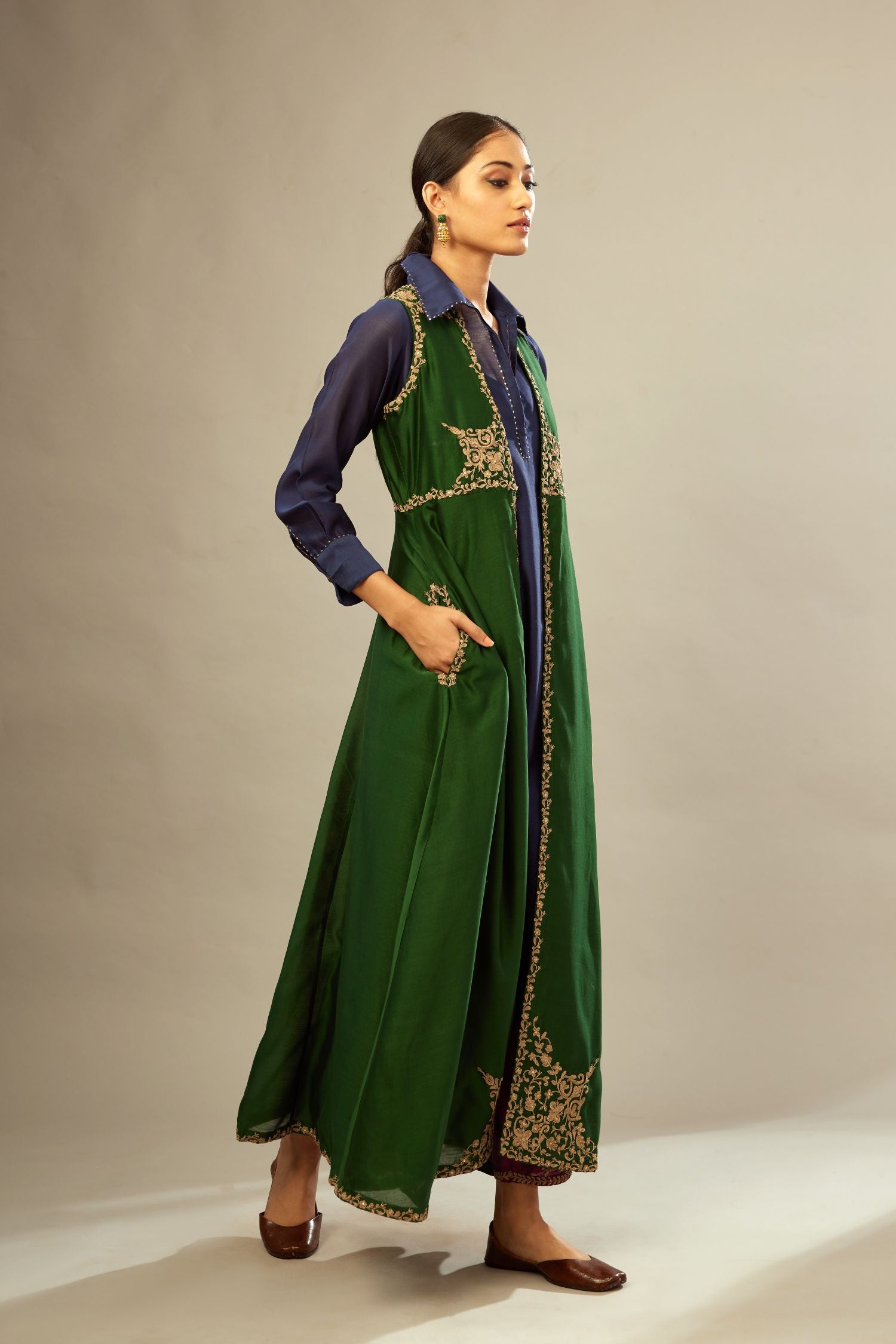 Green long silk chanderi front open sleeveless jacket set with gold dori embroidery detailing, highlighted with gold sequin work.