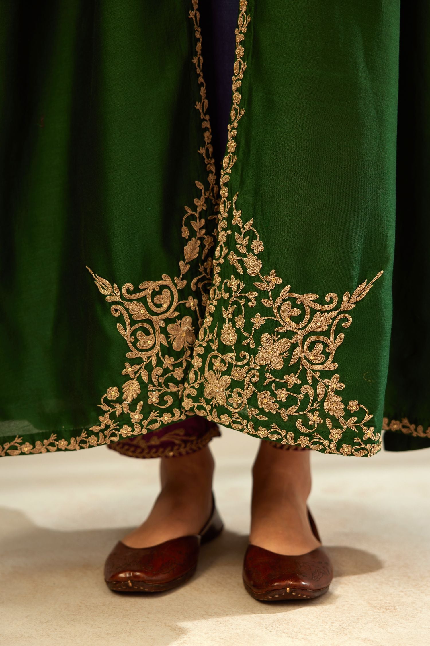 Green long silk chanderi front open sleeveless jacket set with gold dori embroidery detailing, highlighted with gold sequin work.