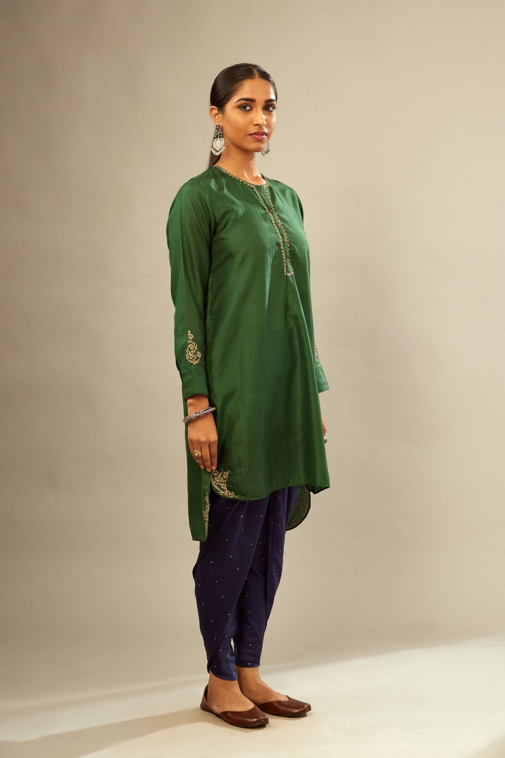 Green silk short kurta set with high-low hem with rounded edges, highlighted with gold zari embroidery.