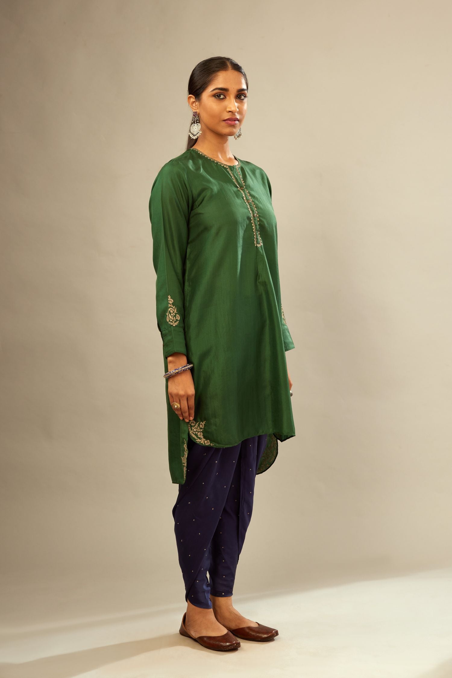 Green silk short kurta set with high-low hem with rounded edges, highlighted with gold zari embroidery.