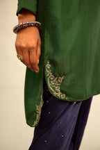 Green silk short kurta set with high-low hem with rounded edges, highlighted with gold zari embroidery.