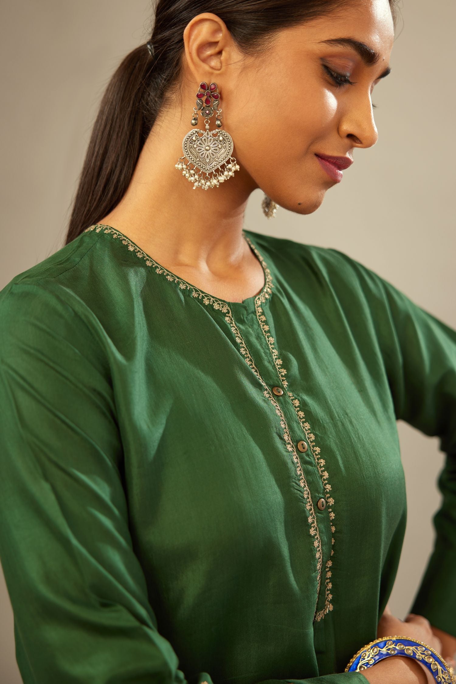 Green silk short kurta set with high-low hem with rounded edges, highlighted with gold zari embroidery.