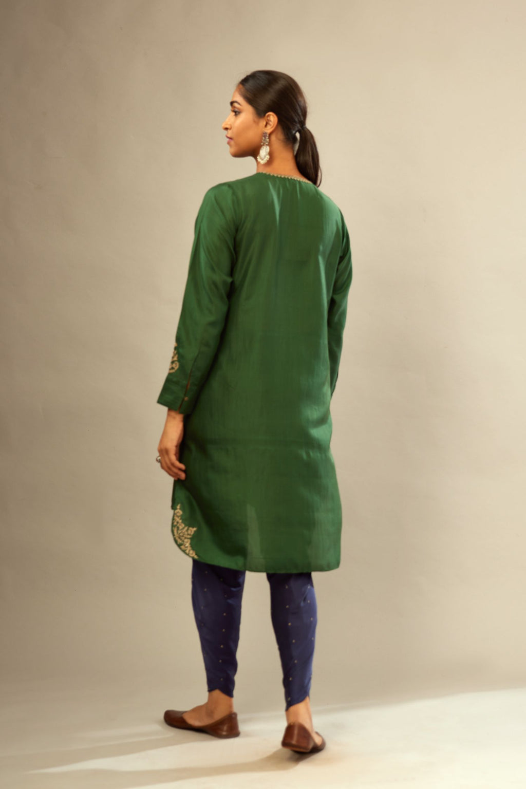 Green silk short kurta set with high-low hem with rounded edges, highlighted with gold zari embroidery.