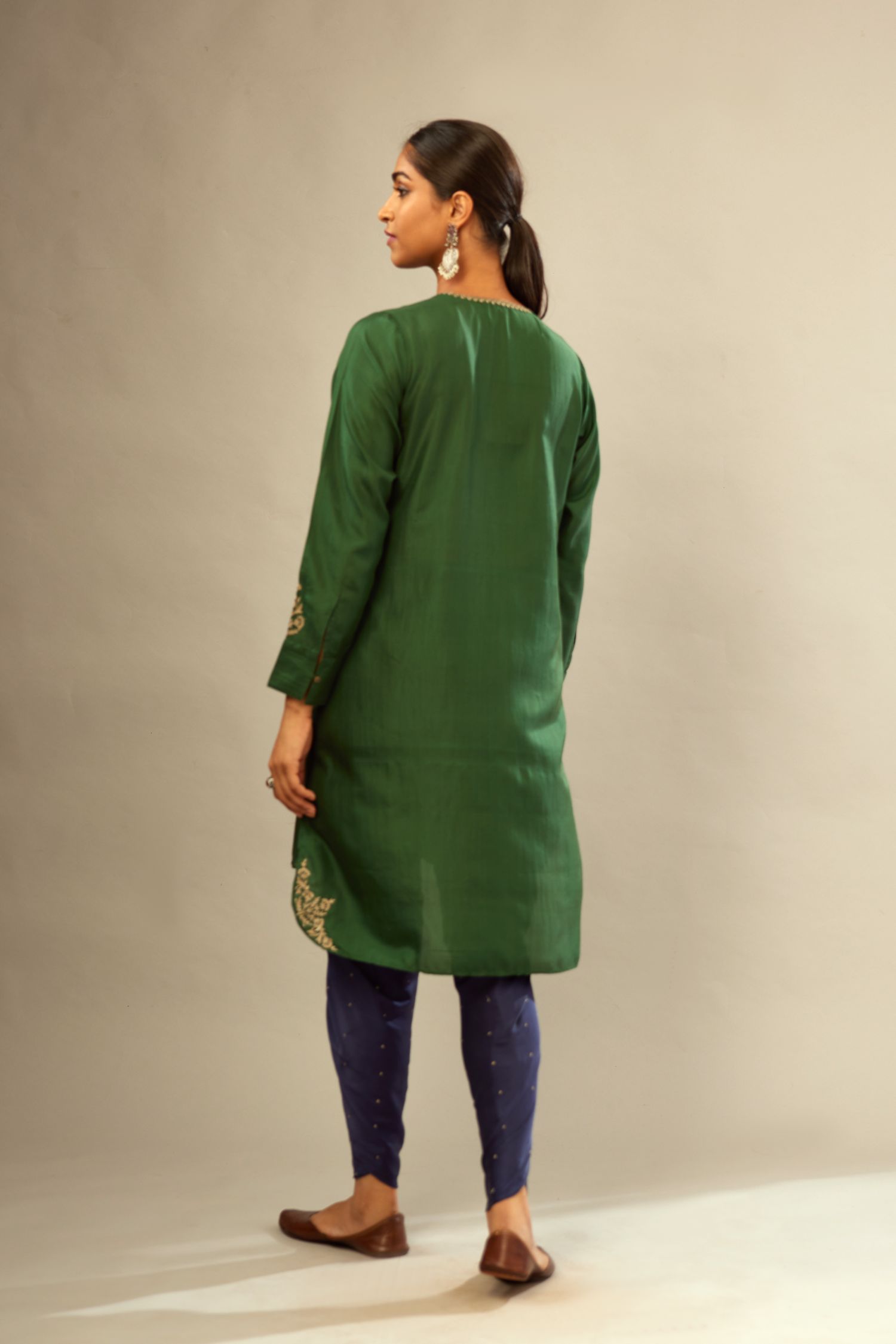 Green silk short kurta set with high-low hem with rounded edges, highlighted with gold zari embroidery.
