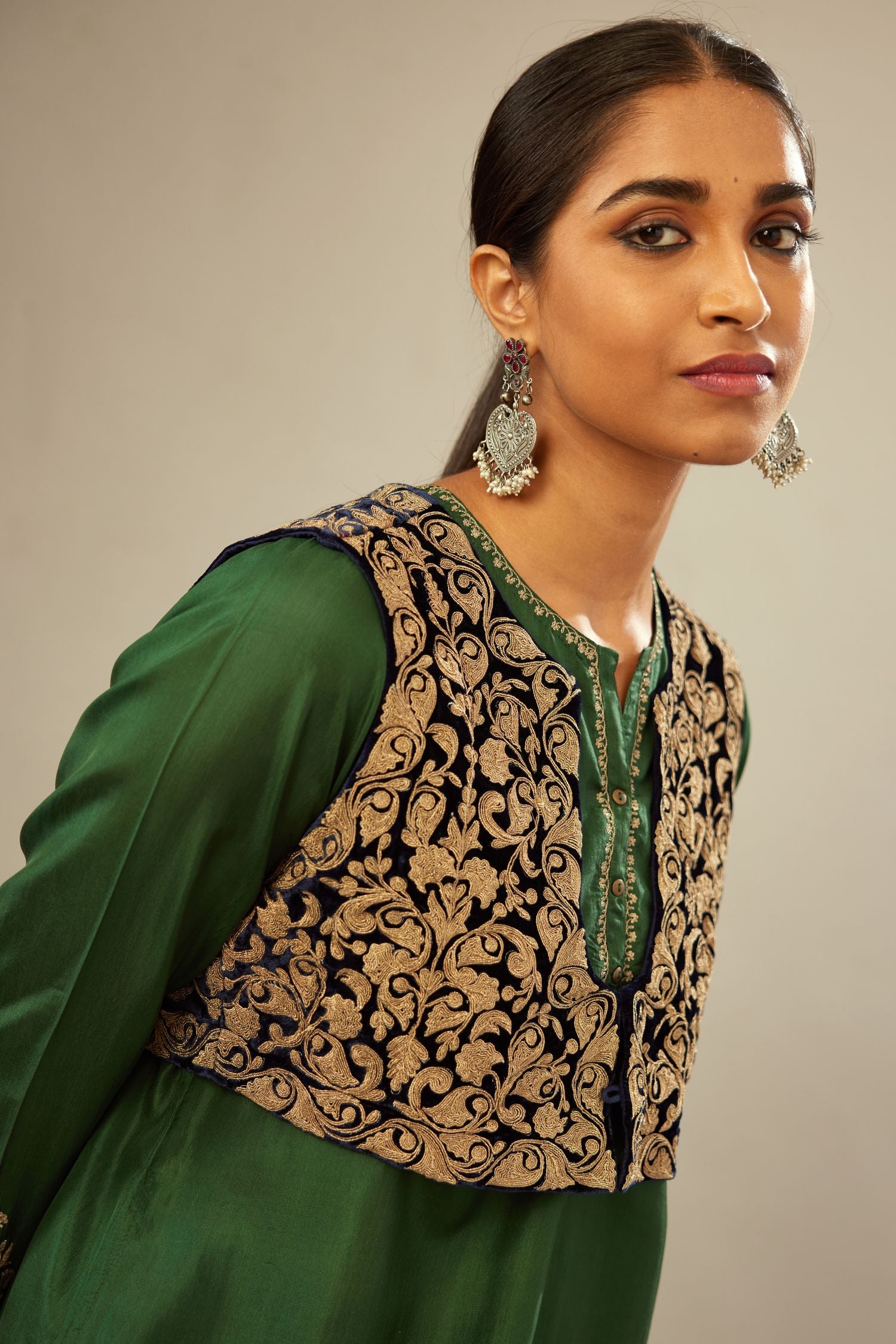 Green silk short kurta set with high-low hem with rounded edges, highlighted with gold zari embroidery.